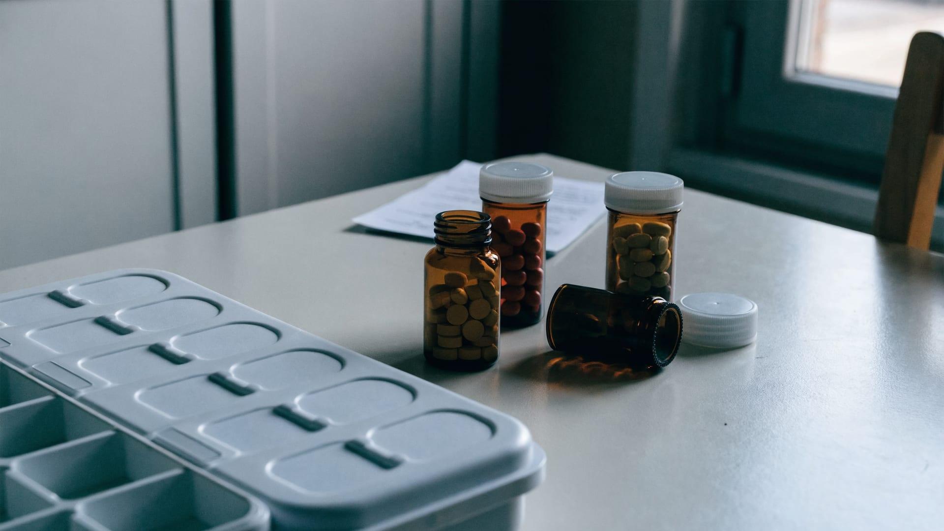 A weekly medication organizer and pill bottles on a kitchen table